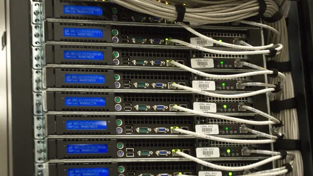 Close-up of the rear of a server rack in a data centre, showing cabling and small blue status displays.