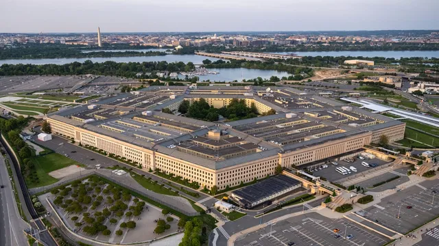 Aerial photograph of the Pentagon building in Washington, D.C., with the Potomac River, Washington Monument and U.S. Capitol visible in the background.