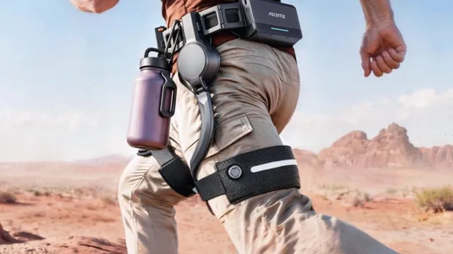 A runner in tan trousers crossing red desert ground, wearing a black powered belt module at the hip with a rigid arm running down the outside of the thigh to a strap above the knee.