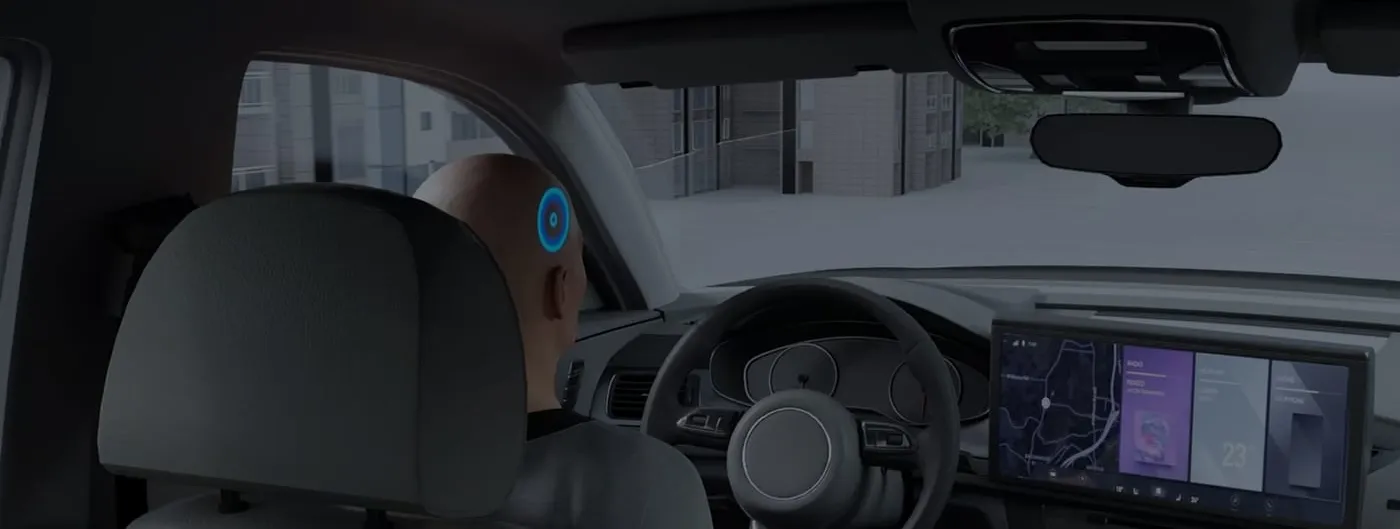 A dark product render seen from the rear seat of a car shows a driver with a glowing blue ring marking a device on the back of the head, facing a lit dashboard display.