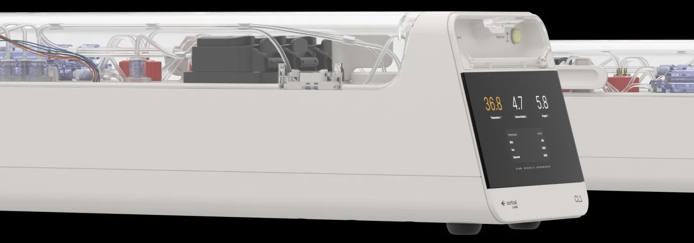 Two Cortical Labs CL1 units side by side, low white enclosures with transparent upper covers showing tubing and circuit boards, the front unit's panel reading a temperature of 36.8 alongside carbon dioxide and oxygen values.
