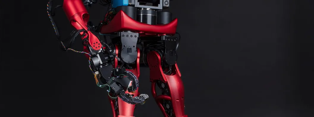 A full-size black humanoid robot standing in a frontal pose against a plain background, with torso, arms, legs and head visible.