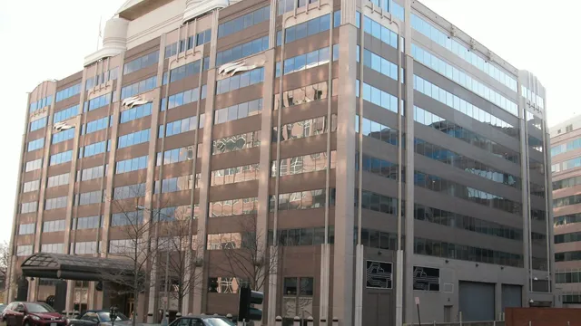 The Federal Communications Commission headquarters at the Portals in Washington, DC — a ten-storey brown brick and glass office block with a curved white parapet, seen from the street corner.