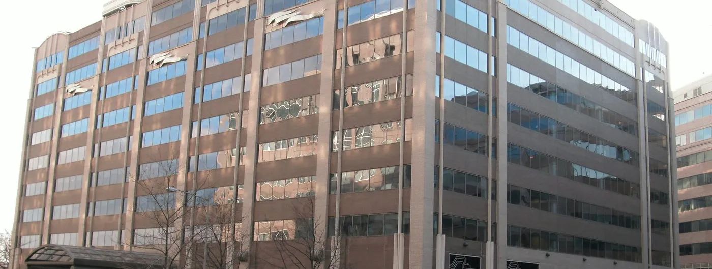 The Federal Communications Commission headquarters at the Portals in Washington, DC — a ten-storey brown brick and glass office block with a curved white parapet, seen from the street corner.