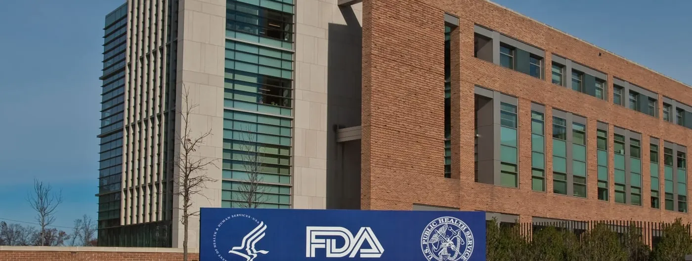 The blue-and-white US Department of Health and Human Services and FDA entrance sign standing in front of FDA Building 21 at the White Oak campus.