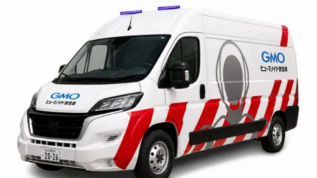A white high-roof van marked with red hazard stripes, a blue light bar and a grey humanoid figure painted on its side panel, photographed against a plain background.