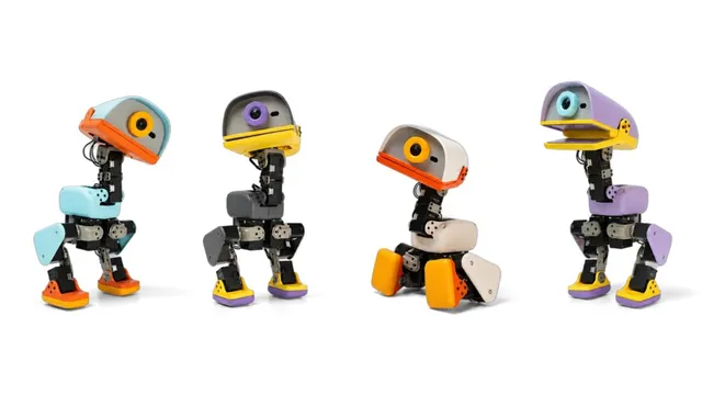 Four small two-legged robots with rounded duck-like heads and coloured panels in orange, grey, cream and purple, standing in a row on a white background.