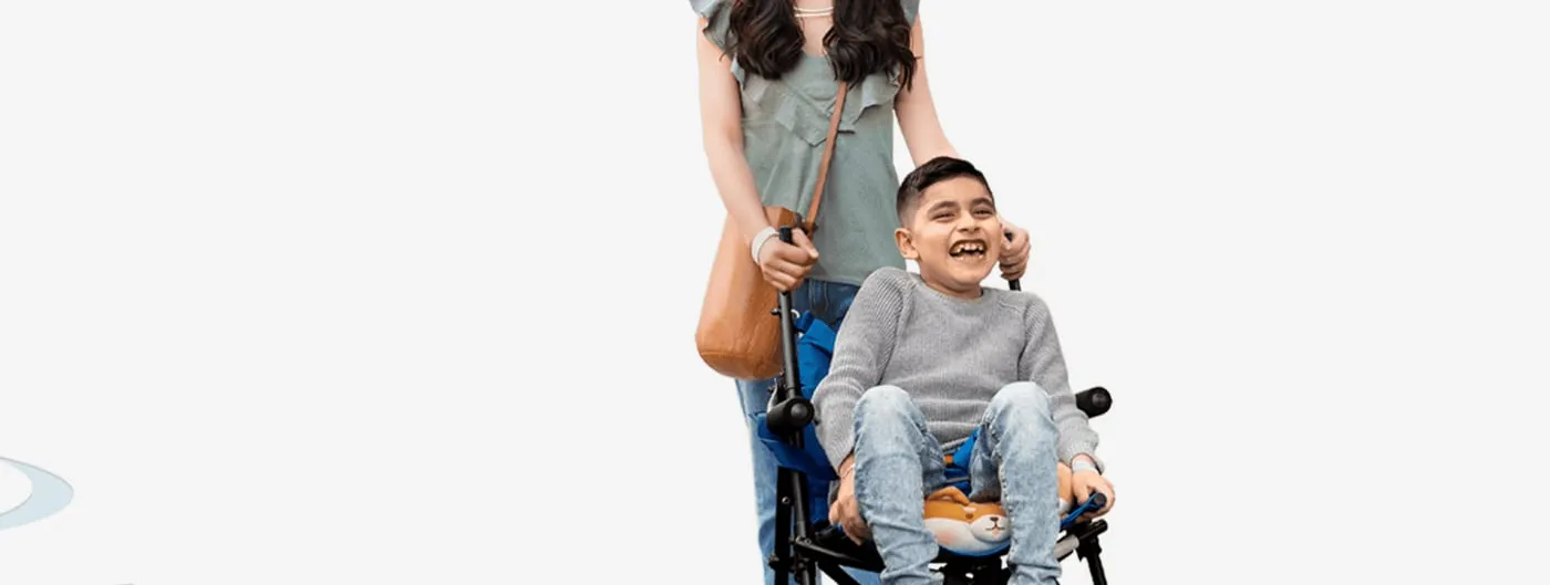 A smiling mother pushes her laughing young son, who sits in an adaptive paediatric wheelchair.