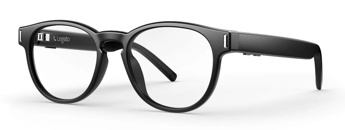 A three-quarter view of Legato black round-framed hearing glasses on a white background, showing the Legato mark and the small microphone and button details on the temple arms.