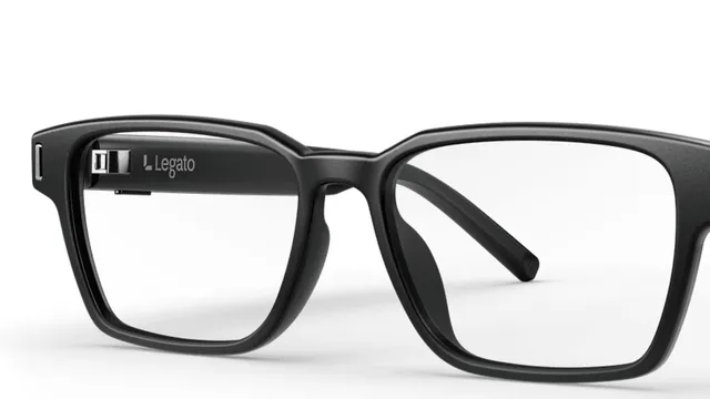 A close-up of matte black eyeglass frames on a white background, with a small module and the Legato name visible inside the left temple arm.