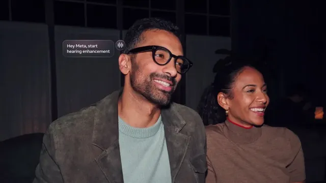 A man wearing black-framed Meta AI glasses smiles at an evening gathering as an on-screen caption reads "Hey Meta, start hearing enhancement" next to a voice waveform icon.