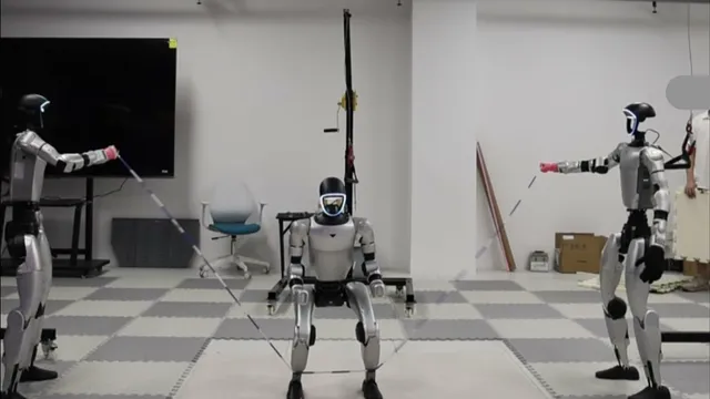 Three Unitree G1 humanoid robots in a laboratory with grey mat flooring: one at each side holds the end of a long rope with an outstretched arm, while the third crouches in the centre between them mid-jump.