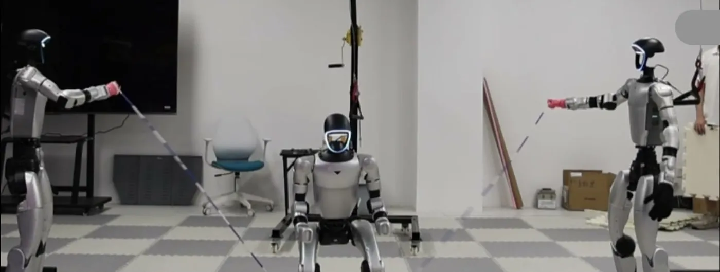 Three Unitree G1 humanoid robots in a laboratory with grey mat flooring: one at each side holds the end of a long rope with an outstretched arm, while the third crouches in the centre between them mid-jump.