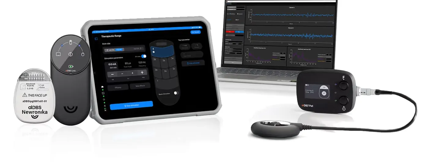 The Newronika αDBS system laid out together: the implantable pulse generator, the αDBS Link and αDBS Pat handheld units, a clinician tablet showing stimulation settings, and a laptop showing brain-signal recordings.