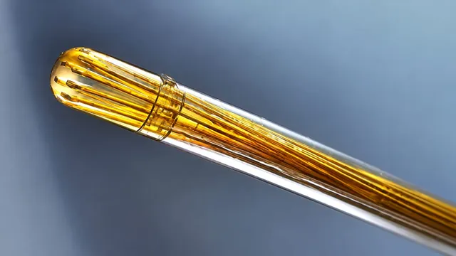 Macro photograph of the Phosphoenix Fountain Probe neural implant, a bundle of gold-coloured microelectrodes emerging from a clear catheter-like shaft against a blue background.