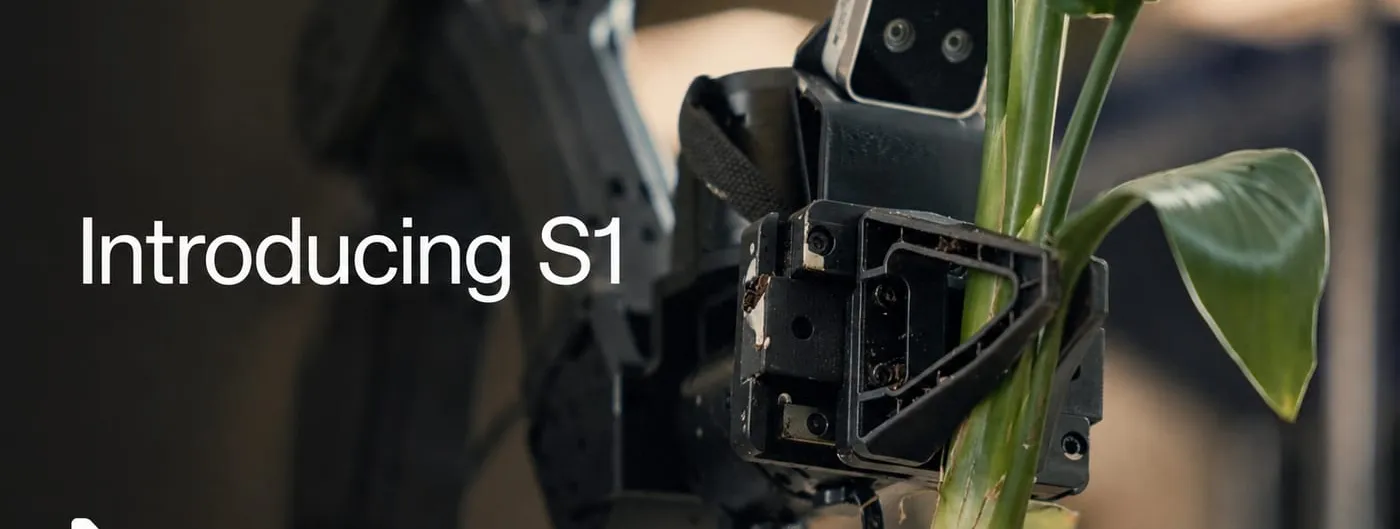 A black robotic gripper with an exposed camera module grasps the stem of a leafy green plant, a second robot arm blurred in the background of an indoor room, with the words Introducing S1 overlaid at left.