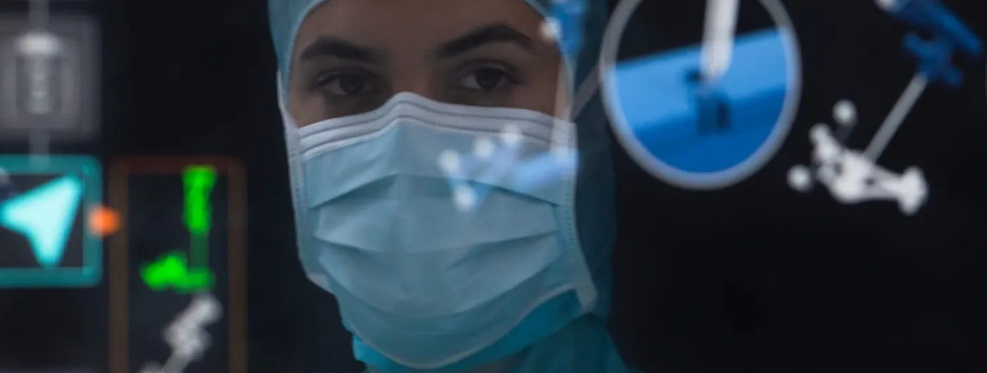 A masked surgeon in a green cap and gown looks through a navigation display overlaid with tracked instrument outlines and a segmented vertebra view.