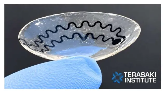 A gloved hand holds a soft, clear smart contact lens printed with a serpentine graphene-and-silver sensor trace around its rim, the Terasaki Institute logo in the corner.