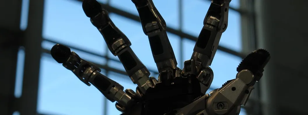 A five-fingered anthropomorphic robotic gripping hand with a pale casing, held palm-forward and mounted on a mechanical wrist.